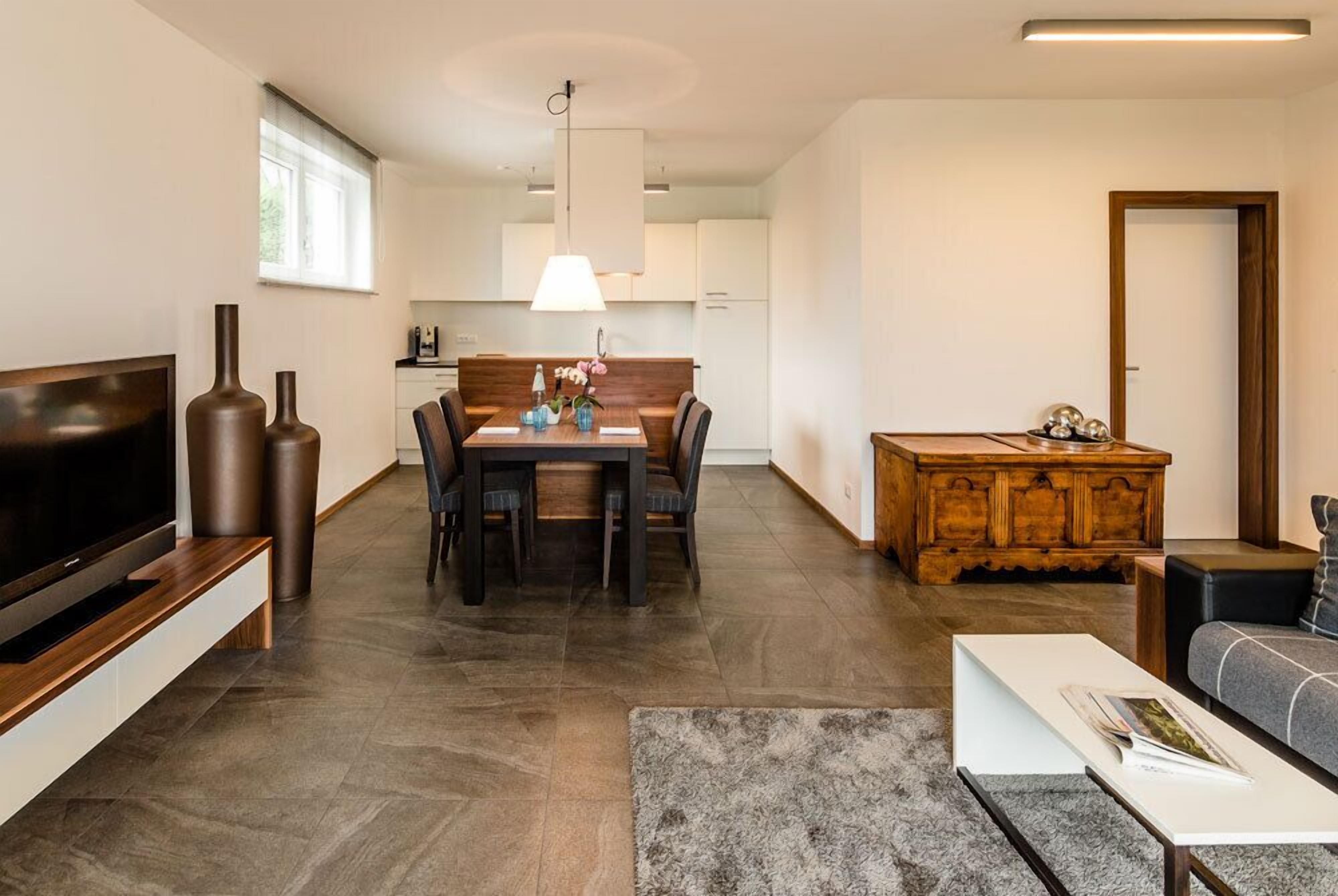 Ein modernes Wohnzimmer mit Flachbildfernseher, einem Holzesstisch mit Stühlen, einem Couchtisch und einem Sofa.