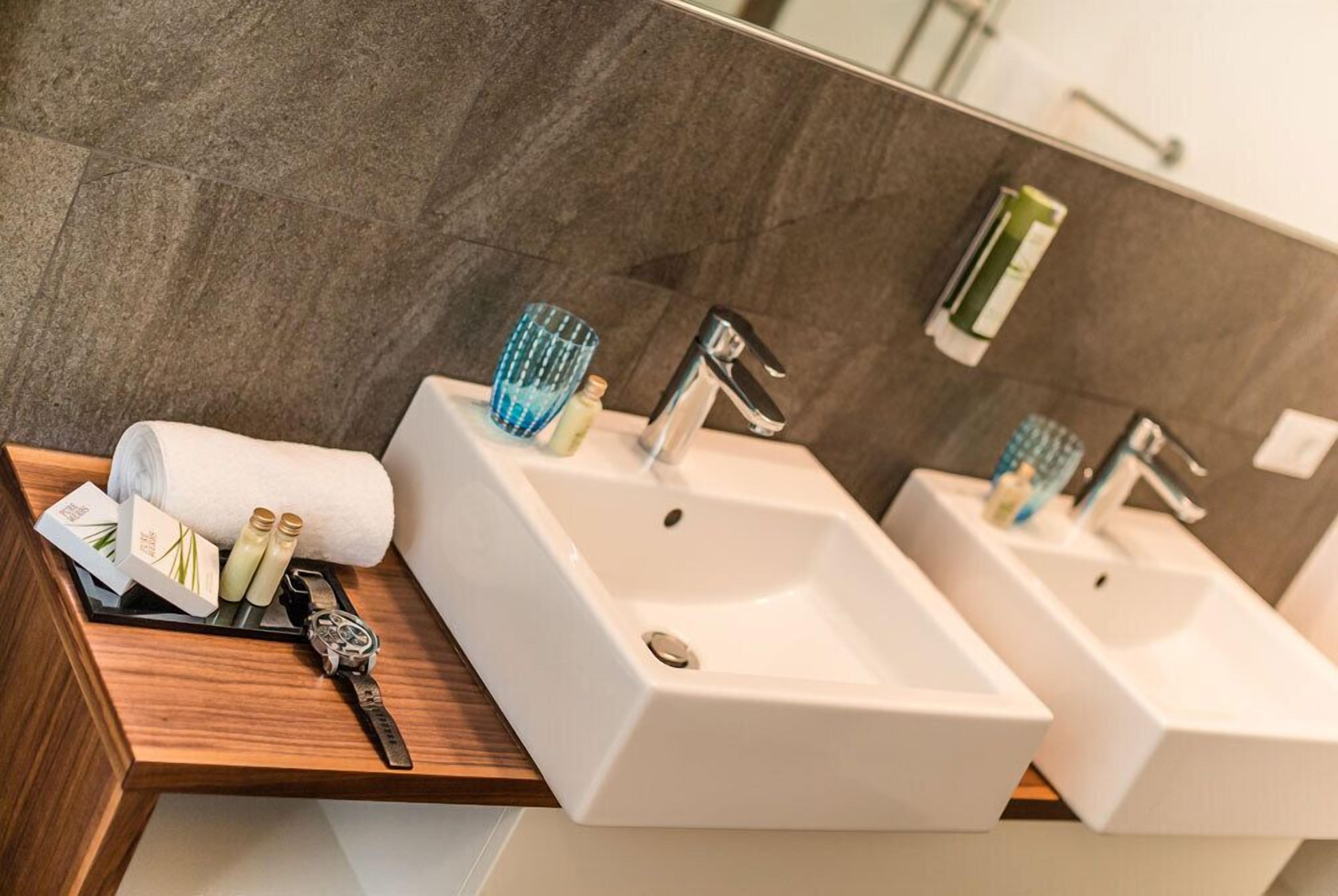 Ein Badezimmer mit zwei Waschbecken, einem Spiegel und einer Holzausstattung für Kosmetikartikel.