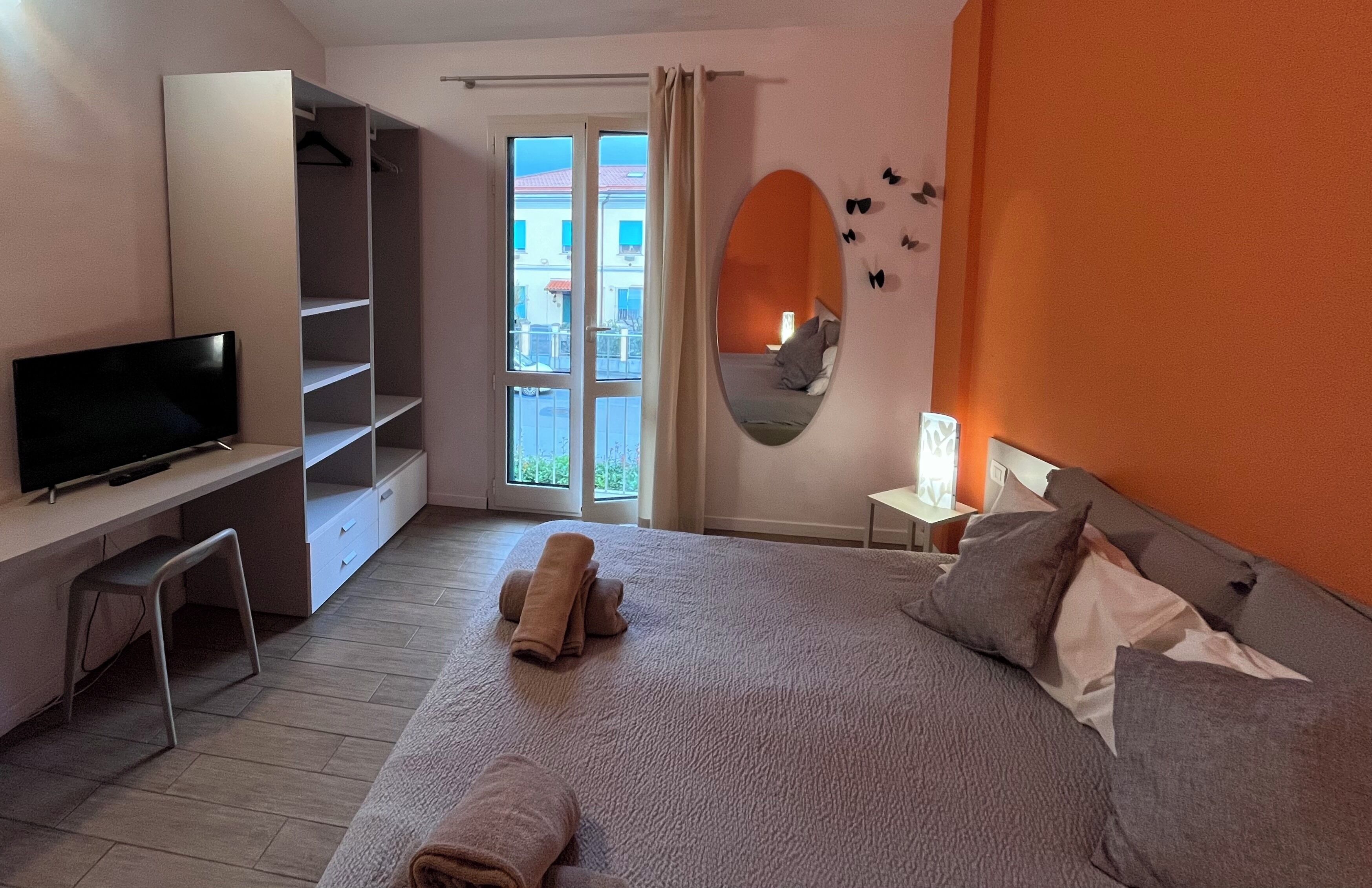Ein Schlafzimmer mit Bett, Fernseher, Schreibtisch und Kleiderschrank.