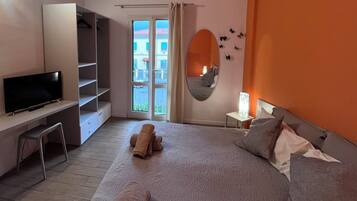 Ein Schlafzimmer mit Bett, Fernseher, Schreibtisch und Kleiderschrank.