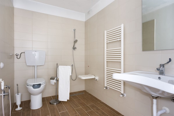 A bathroom with a toilet, shower, and sink.