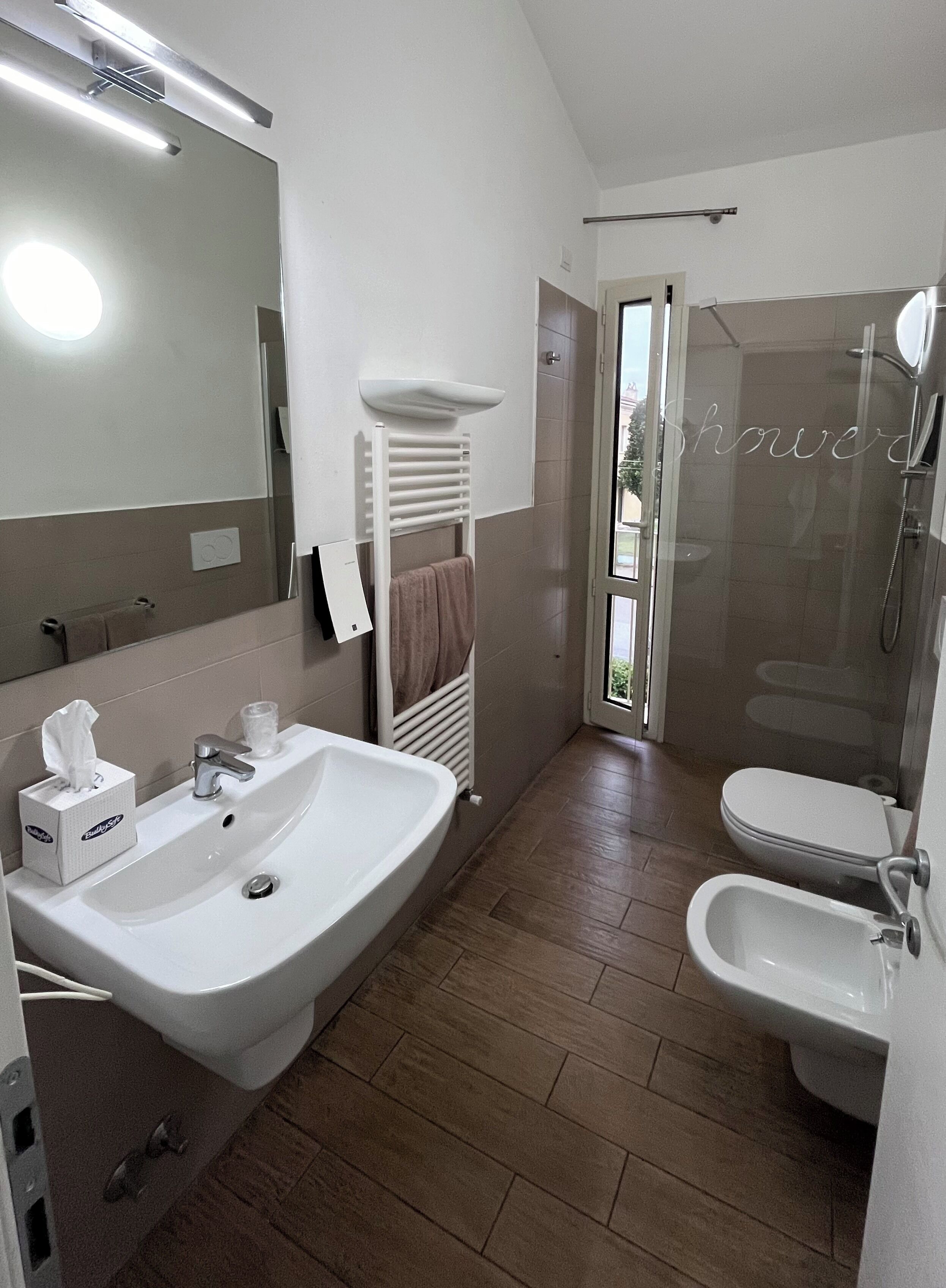 Une salle de bain moderne dotée d’un grand lavabo, d’un bidet, de toilettes et d’une douche à parois de verre.