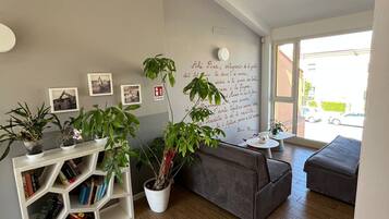 Una sala de estar moderna con una estantería, un sofá gris y un ventanal grande.