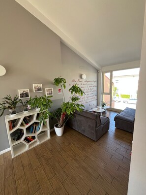 Una sala de estar moderna con una estantería, un sofá gris y un ventanal grande.