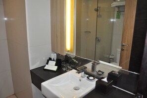 Een moderne badkamer met een wit wastafelmeubel, een douchecabine met glazen wanden en een grote spiegel.