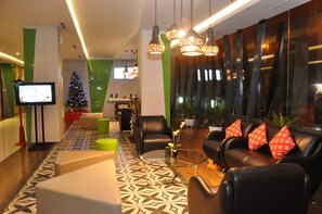 Een moderne lobby met lederen zitplaatsen, een glazen bijzettafeltje en een kerstboom.