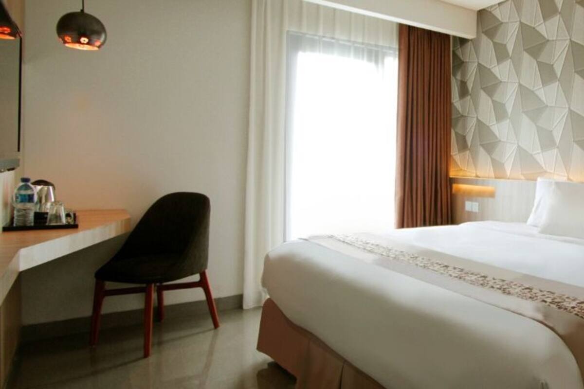 Hotellihuone, jossa on sänky, työpöytä ja tuoli.