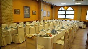 A banquet hall with long tables set for dining, featuring chairs with headrests and tablecloths. - Hostal Venecia (Azagra)