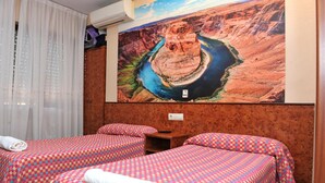 A hotel room with two beds, a large painting of a canyon, and a window with curtains. - Hostal Venecia (Azagra)