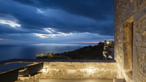 Un edificio in pietra con vista sul mare al crepuscolo.