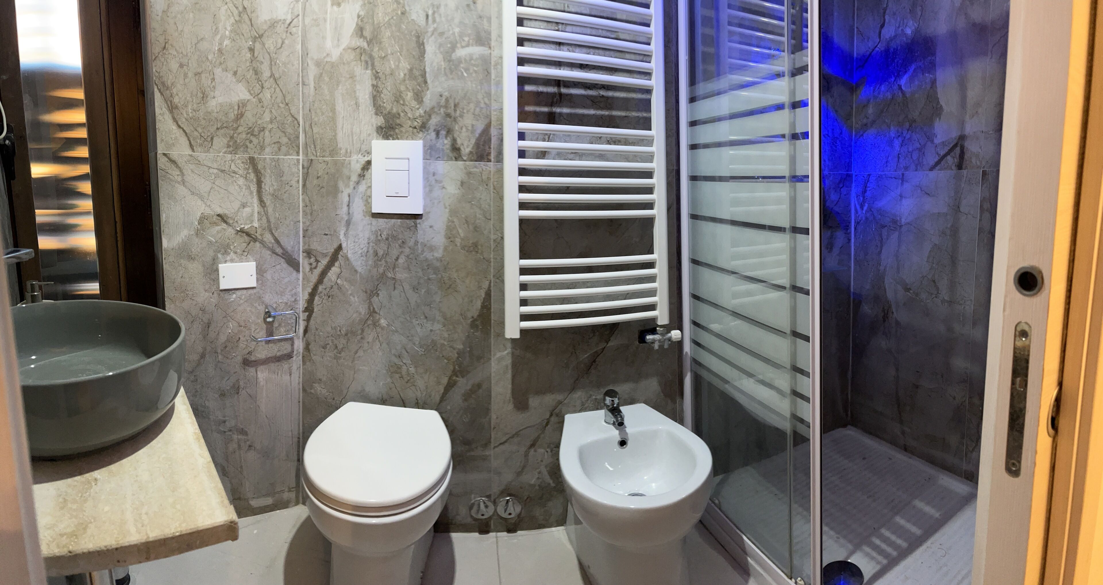 Une salle de bain comprenant des toilettes, un bidet et une douche séparée par une paroi en verre.