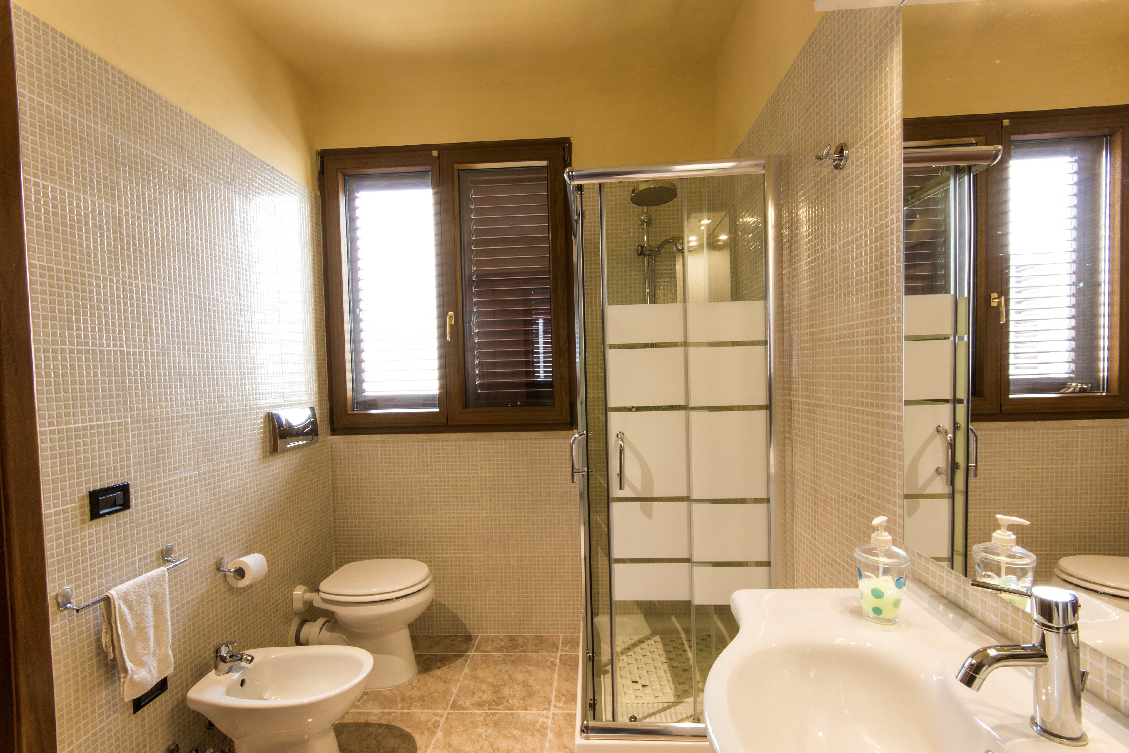 A bathroom with a glass-enclosed shower, a sink with a mirror, and a toilet.