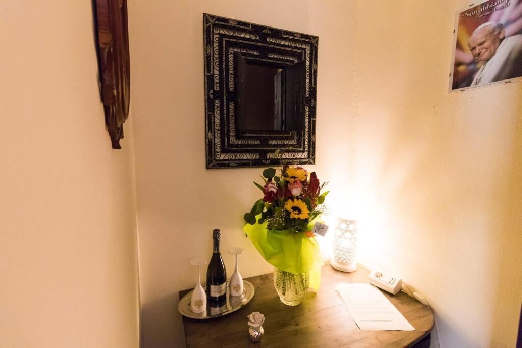 A small table with a bouquet of flowers, a bottle of wine, and a candle.