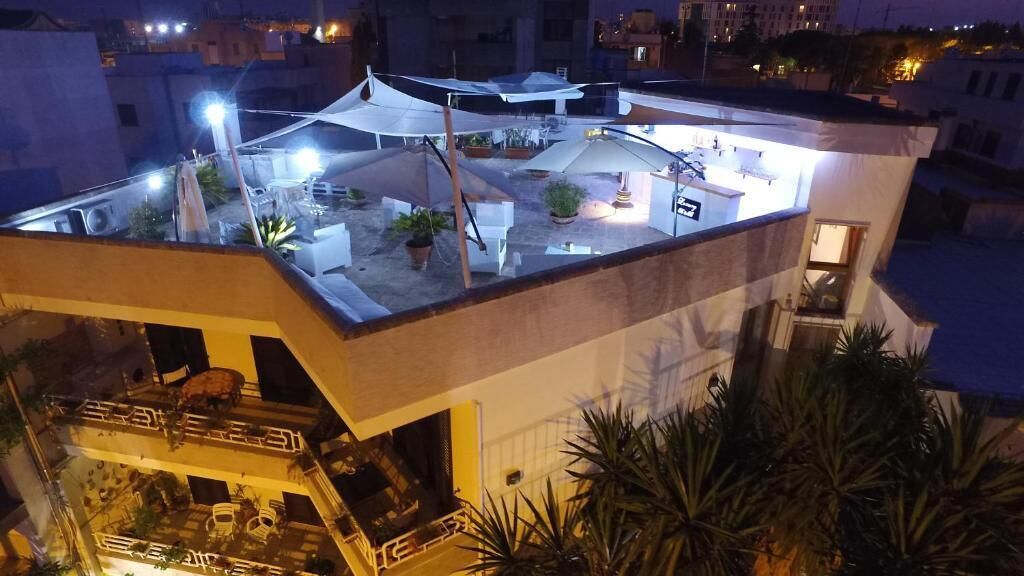 A rooftop terrace with outdoor seating, potted plants, and a well-lit area.
