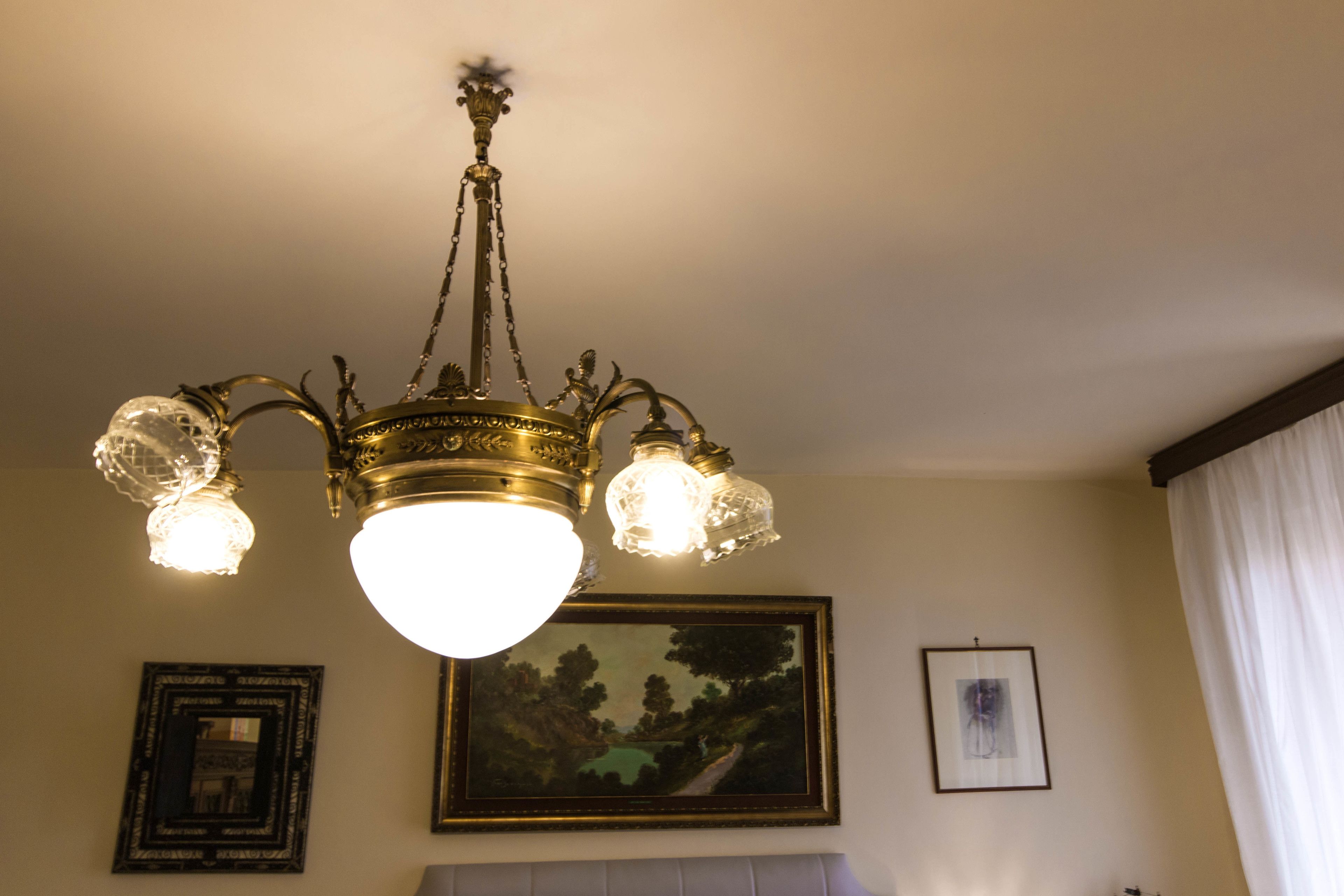A chandelier with multiple light fixtures and a painting on the wall.
