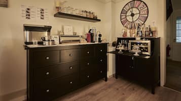 A kitchen with a coffee maker, toaster, and various kitchen appliances. There is a clock on the wall and a shelf with jars and bottles.