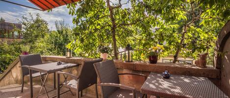 An outdoor patio with wicker furniture, a red awning, and potted plants.