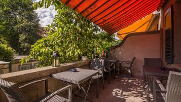 Une terrasse extérieure avec des meubles en osier, un auvent rouge et des plantes en pot.