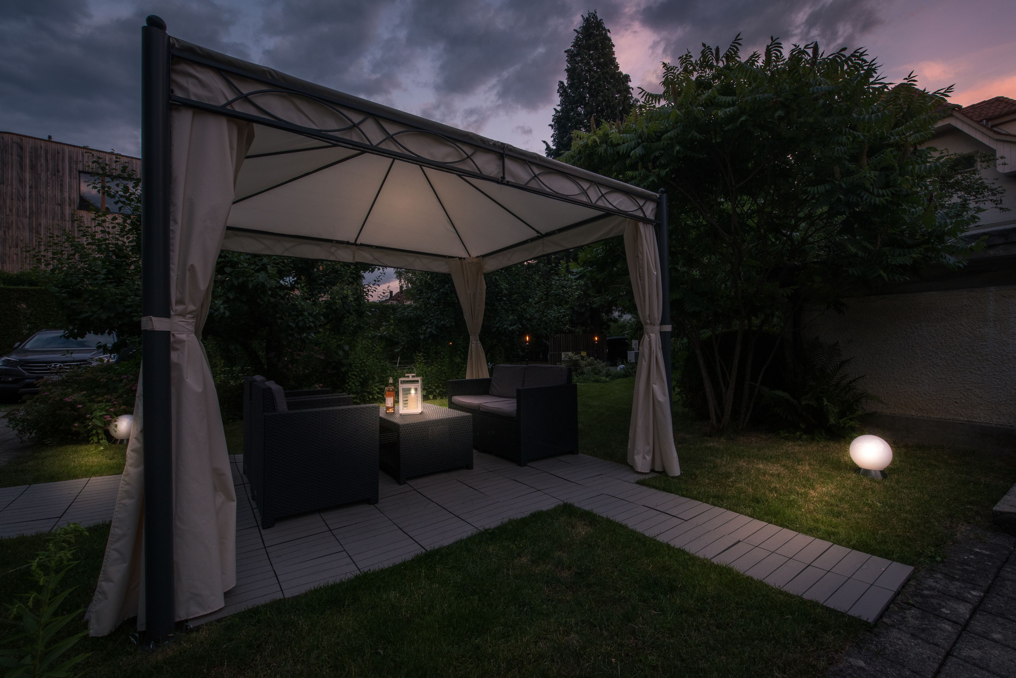 An outdoor patio with a canopy, seating area, and ambient lighting.