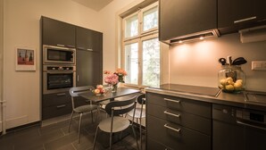 Uma cozinha moderna com armários escuros, forno embutido e um espaço de jantar com mesa e cadeiras.