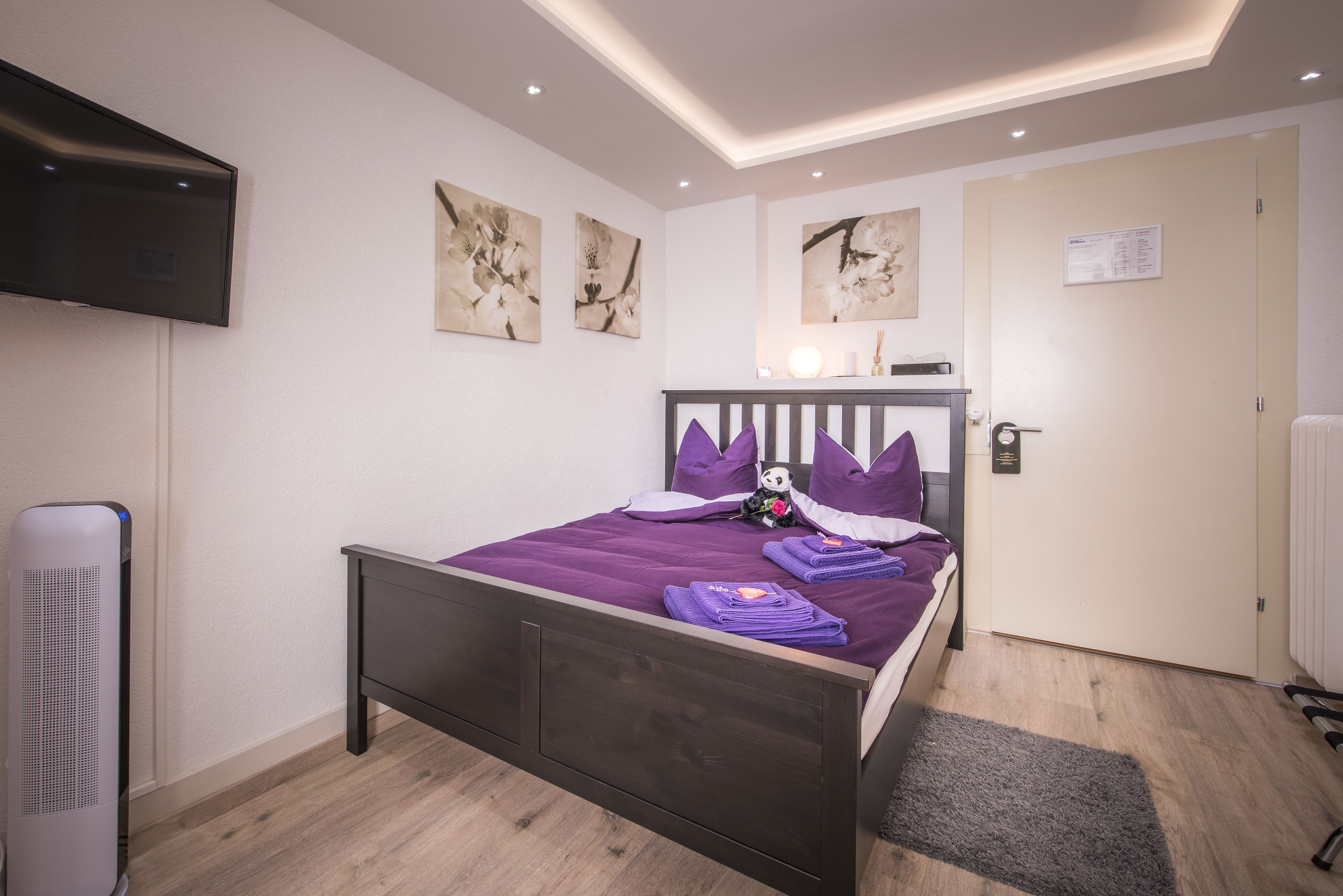 Une chambre à coucher avec un lit, un téléviseur à écran plat et des œuvres d’art accrochées aux murs.