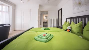 Un dormitorio con una colcha verde, un peluche de panda y una almohada verde.