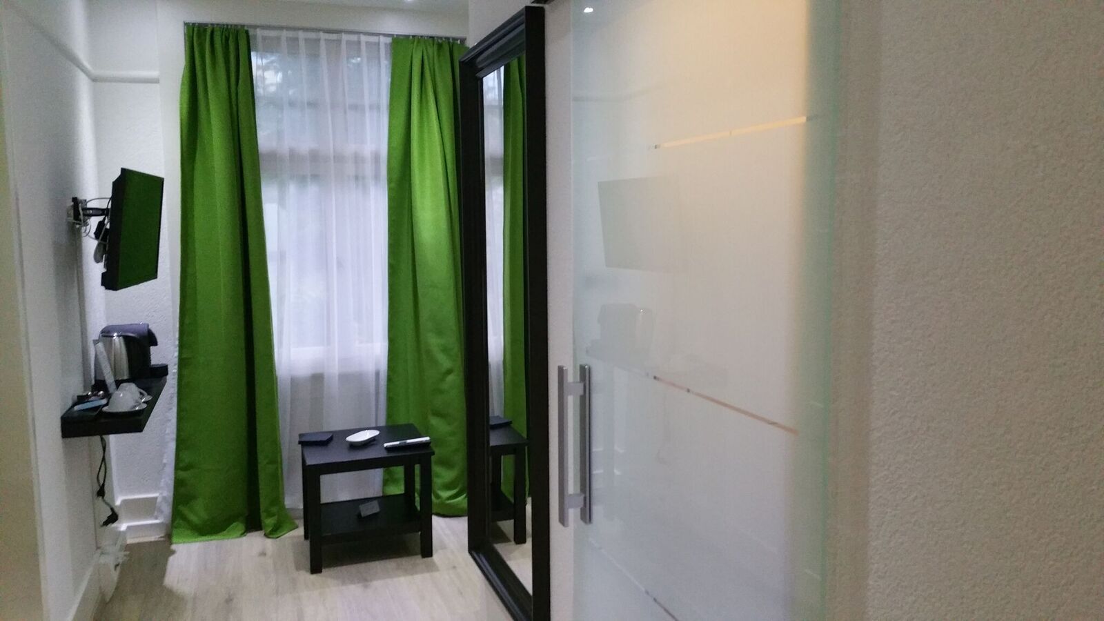 Une chambre d’hôtel équipée d’un bureau, d’une chaise, d’une petite table, d’un miroir et d’une armoire.