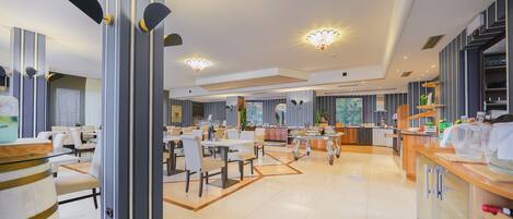 A modern dining area with high ceilings, pendant lighting, and a central island.