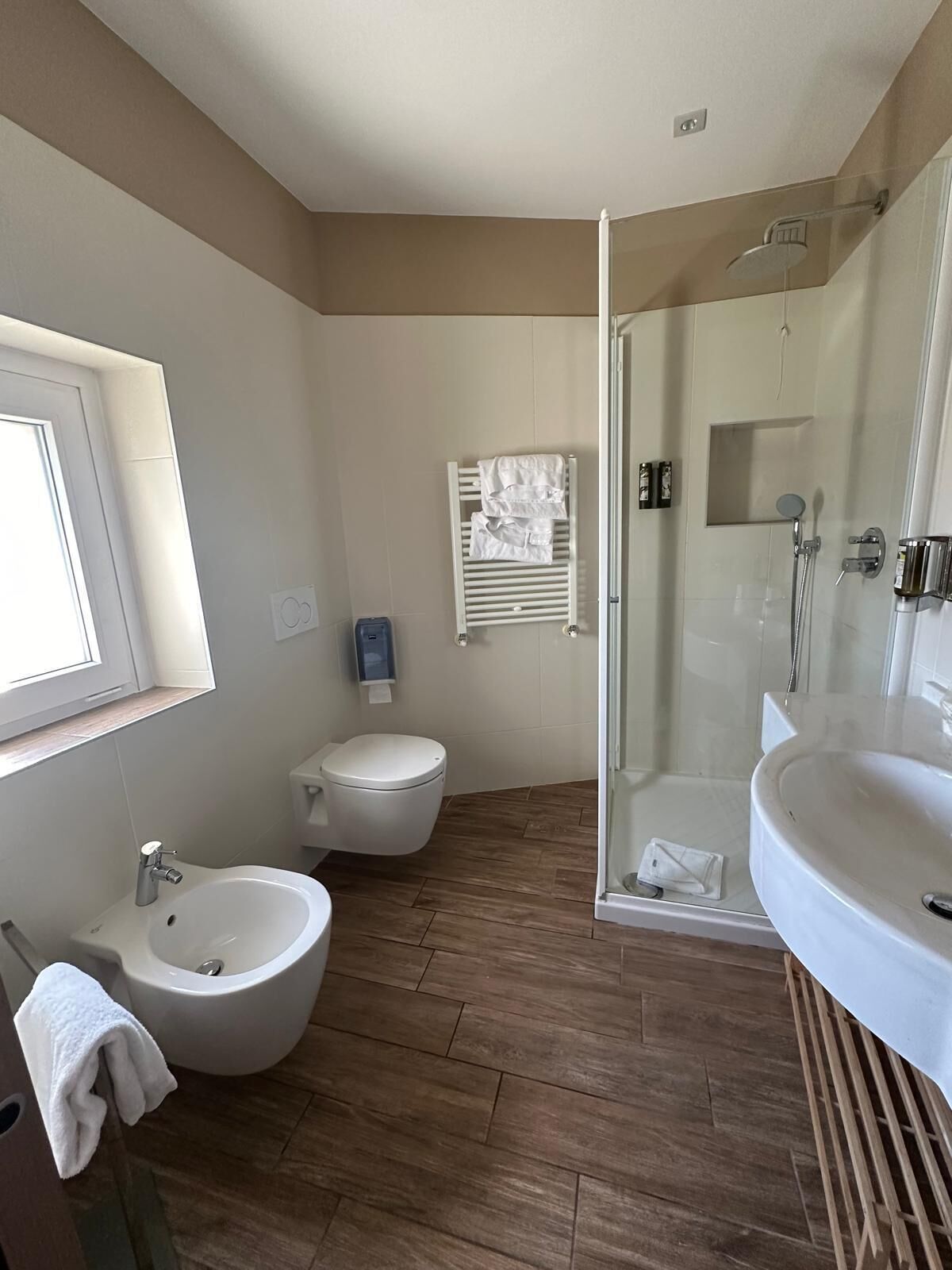 A modern bathroom with a bidet, toilet, and a glass-enclosed shower.
