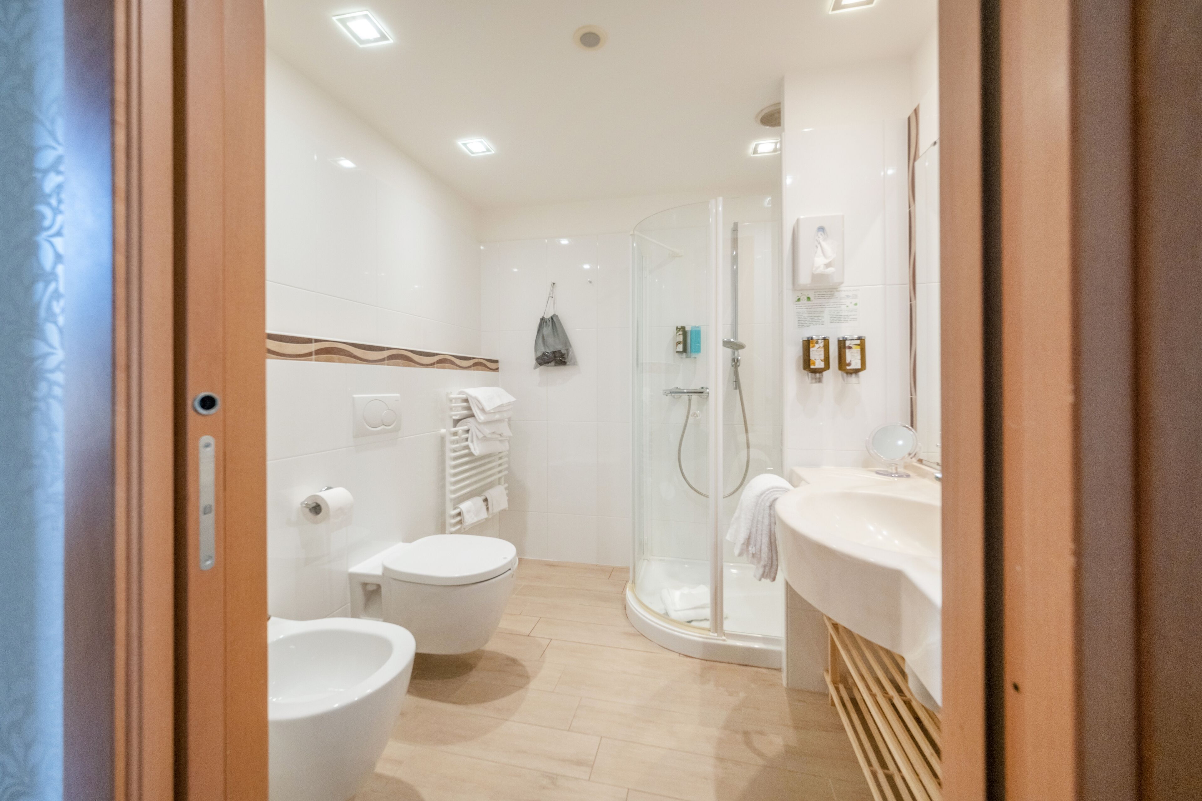 A modern bathroom with a toilet, bidet, and a glass-enclosed shower area.