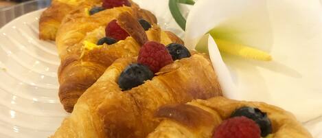 Een bord croissants, gegarneerd met bessen en een witte bloem.