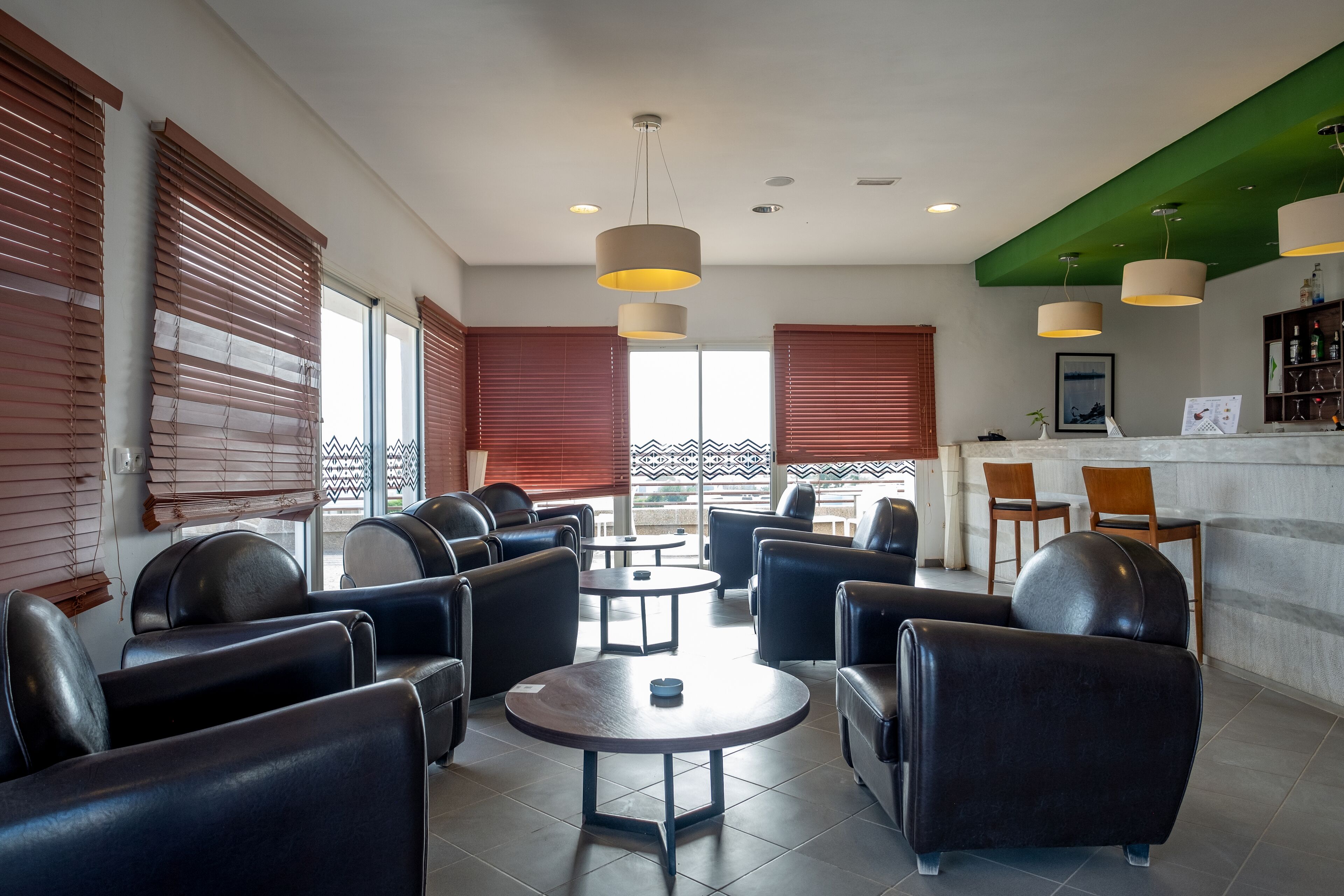 Un espacio lounge moderno con sofás de cuero, mesas redondas e iluminación colgante.