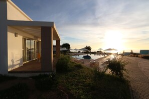 A modern building with a covered outdoor area, a swimming pool, and a sunset view. - Lunja Village Taghazout (Tamri)
