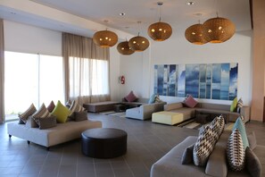 A spacious living room with multiple seating areas, large windows, and a modern chandelier. - Lunja Village Taghazout (Tamri)