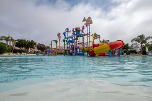 A water park with various play structures and slides over a pool. - Lunja Village Taghazout (Tamri)