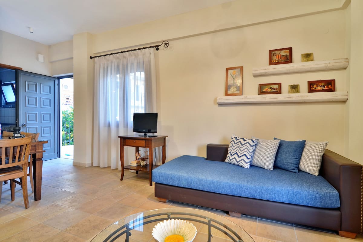 A living room with a sofa, television, and a dining area with a table and chairs.