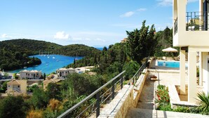 A coastal villa with a swimming pool, a view of the sea, and a hillside with buildings. - Niriides Apartments (Igoumenitsa)