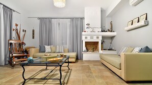 A living room with a sofa, a coffee table, a fireplace, and a bookshelf. - Niriides Apartments (Igoumenitsa)