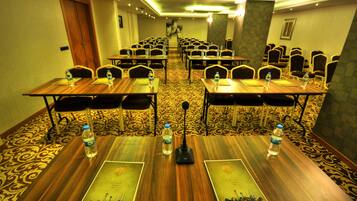 A conference room with rows of tables, each with a water bottle and a microphone.