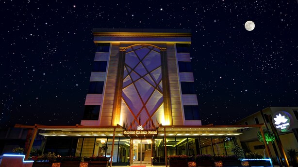 The exterior of the Golden Deluxe Hotel with a prominent entrance, illuminated signage, and a night sky with stars and a visible moon. - Golden Deluxe Hotel (Adana)