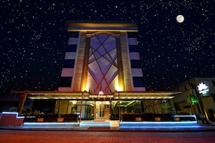 El exterior del Hotel Golden Deluxe, con una entrada destacada, señalización iluminada y un cielo nocturno con estrellas y luna visible.