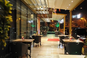 Un comedor interior con mesas y sillas, un muro de cristal y una alfombra roja.