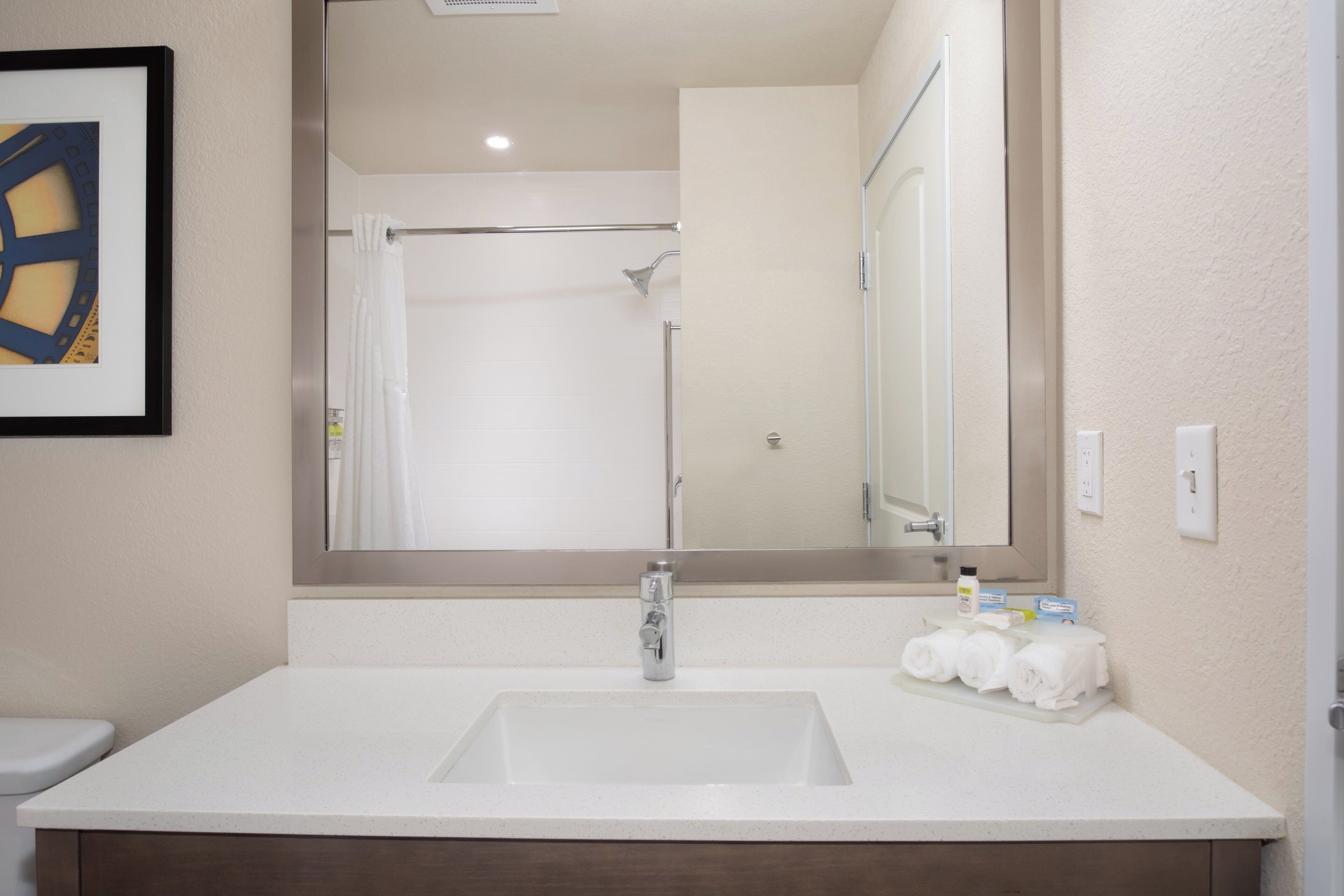 A bathroom with a white sink, a mirror, and a shower.