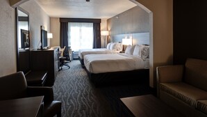 A hotel room with two beds, a desk, a chair, and a sofa. - Holiday Inn Express & Suites Manhattan by IHG (Manhattan)