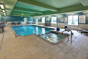An indoor swimming pool with a diving board, pool lift, and lounge area with chairs and tables. - Holiday Inn Express & Suites Manhattan by IHG (Manhattan)