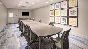A conference room with a long table, chairs, a flat-screen TV, and patterned wall art. - Holiday Inn Express & Suites Manhattan by IHG (Manhattan)