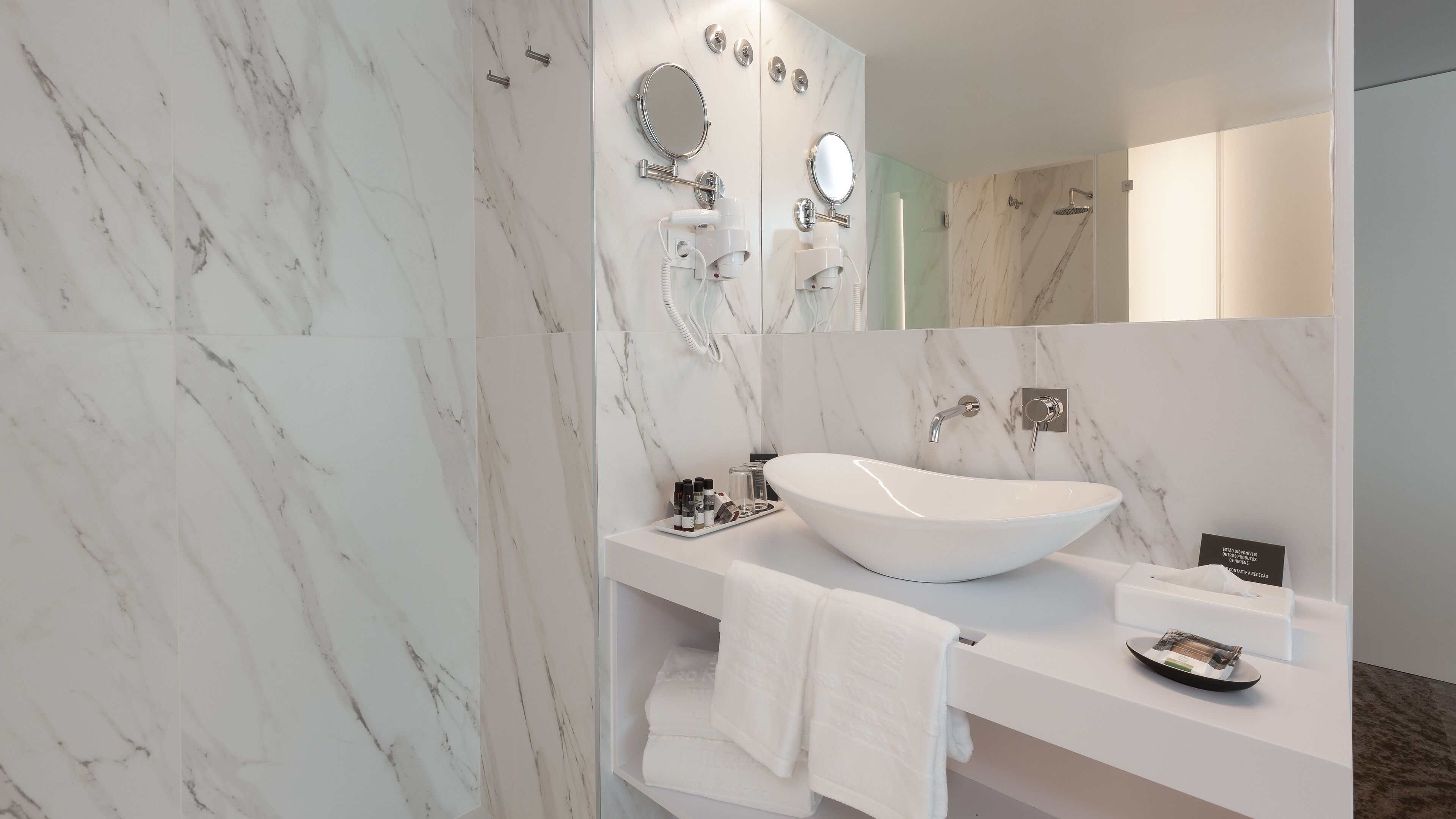 A modern bathroom with a large oval sink, a mirror, and a shower.