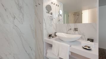 A modern bathroom with a large oval sink, a mirror, and a shower.