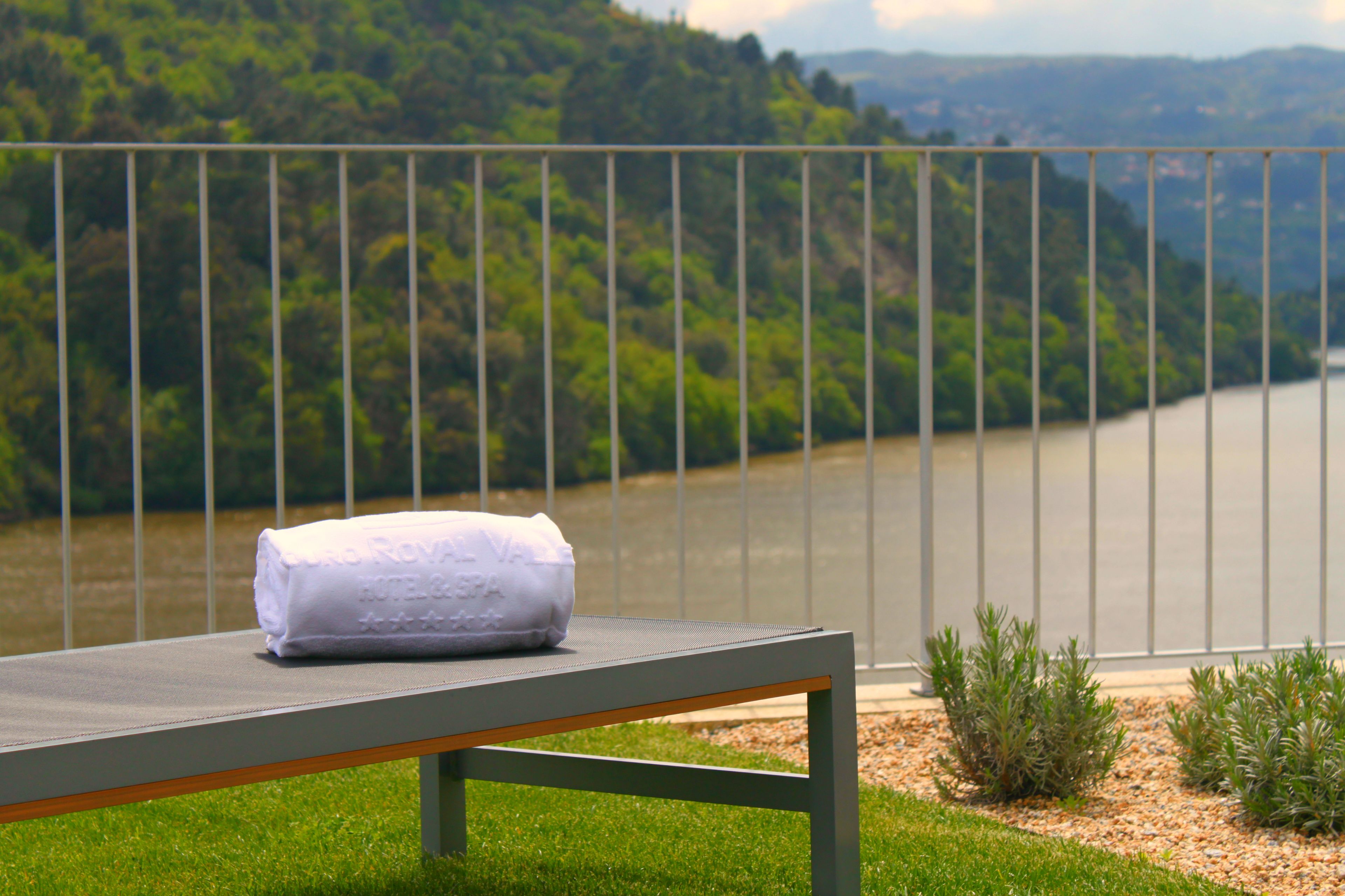 A bench with a towel on it, overlooking a river and greenery.