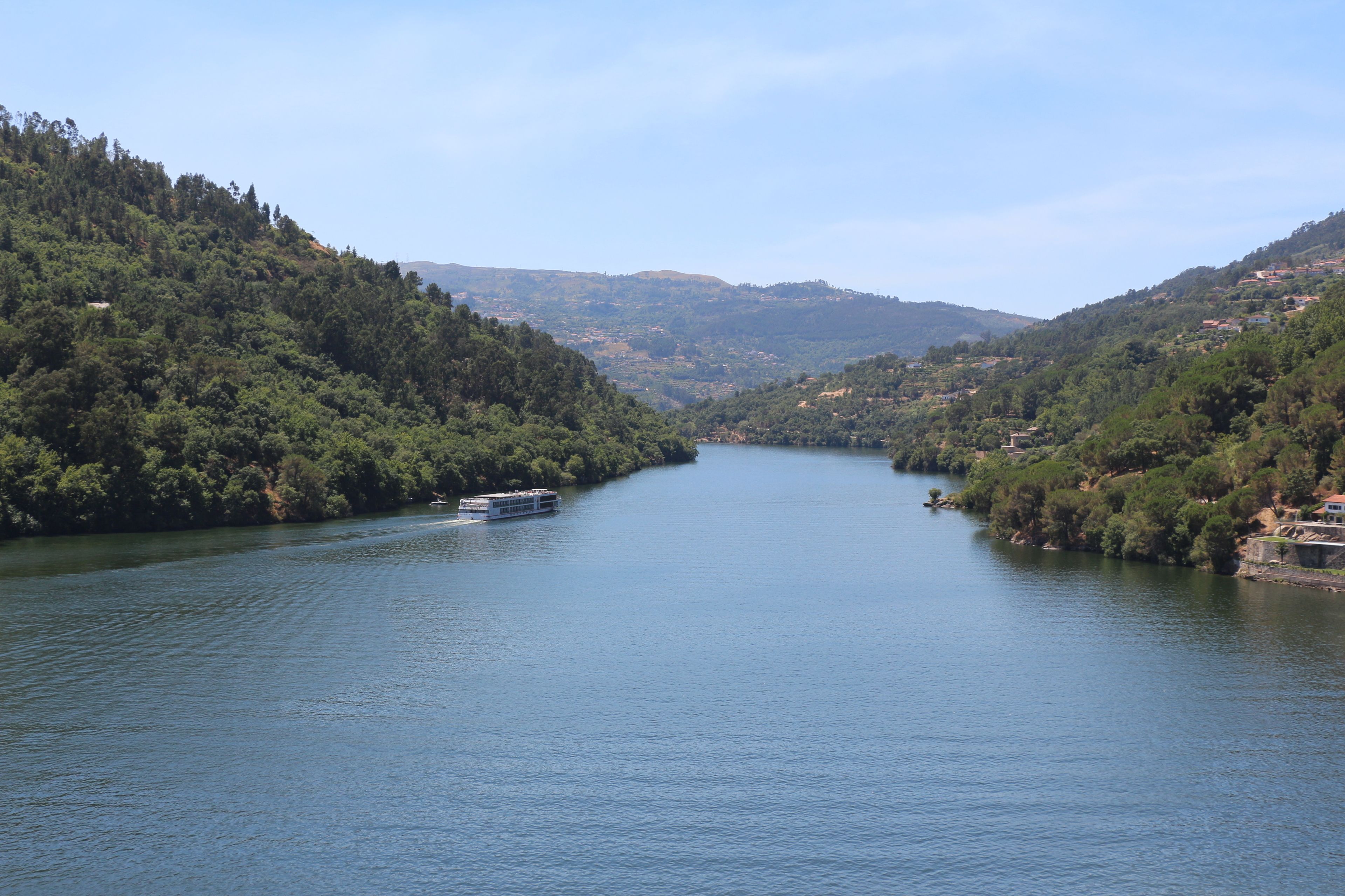 A river with a boat, surrounded by forested hills.